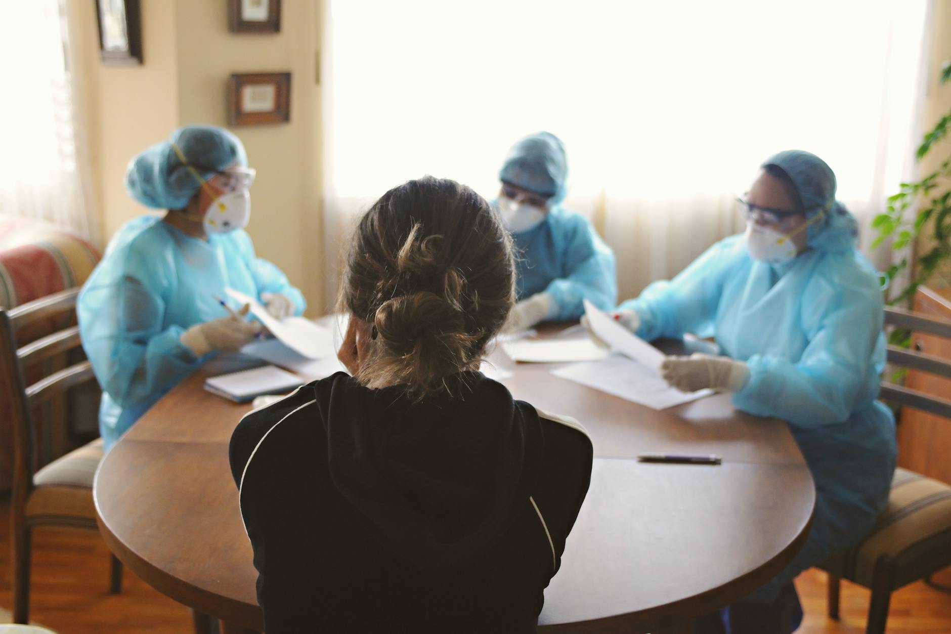 Lekarze w środkach ochrony indywidualnej rozmawiają z pacjentem w gabinecie