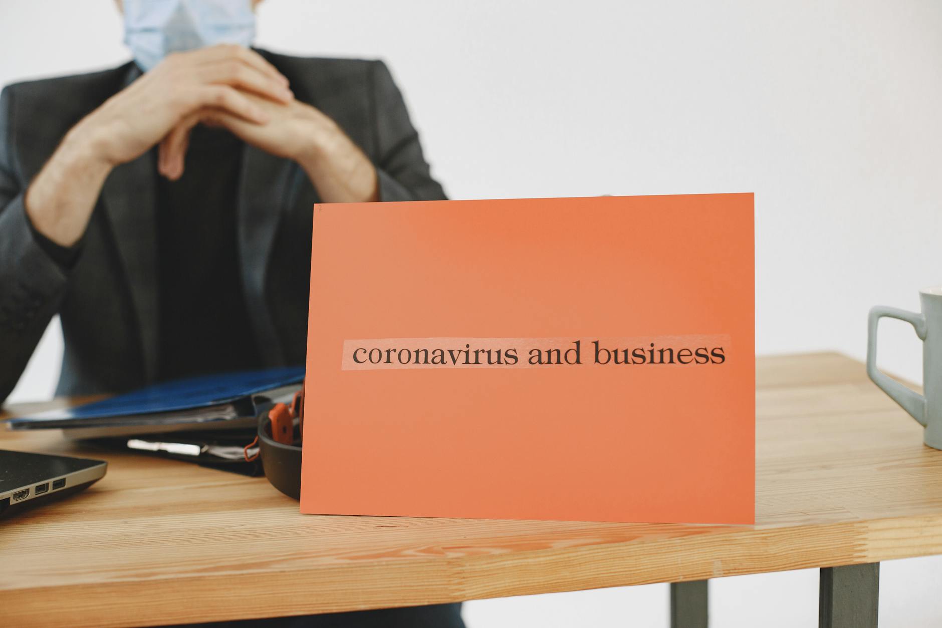 Biznesmen trzymający tabliczkę z napisem coronavirus impact