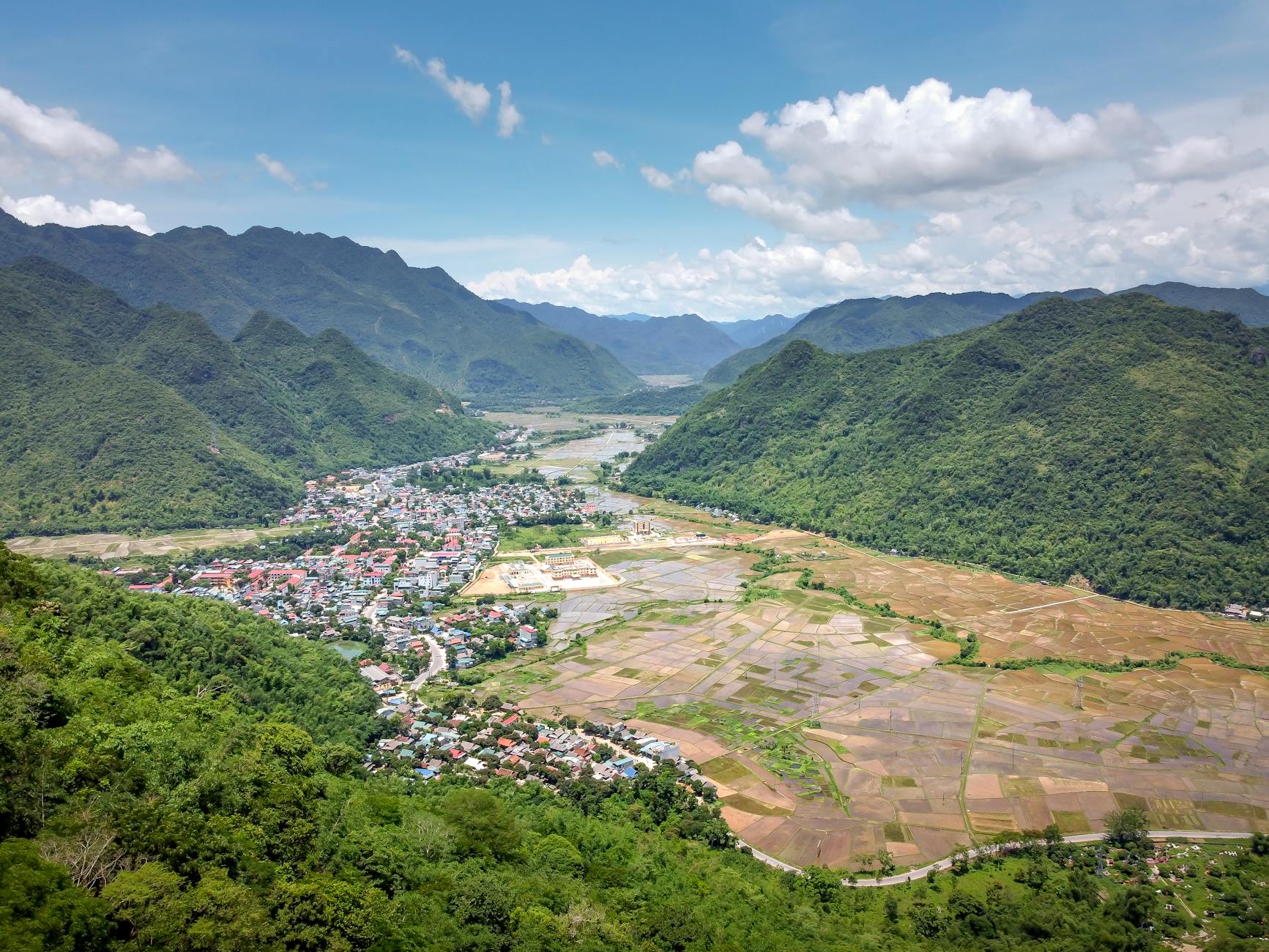 Górska dolina z zielenią i miastem w tle w słoneczny dzień