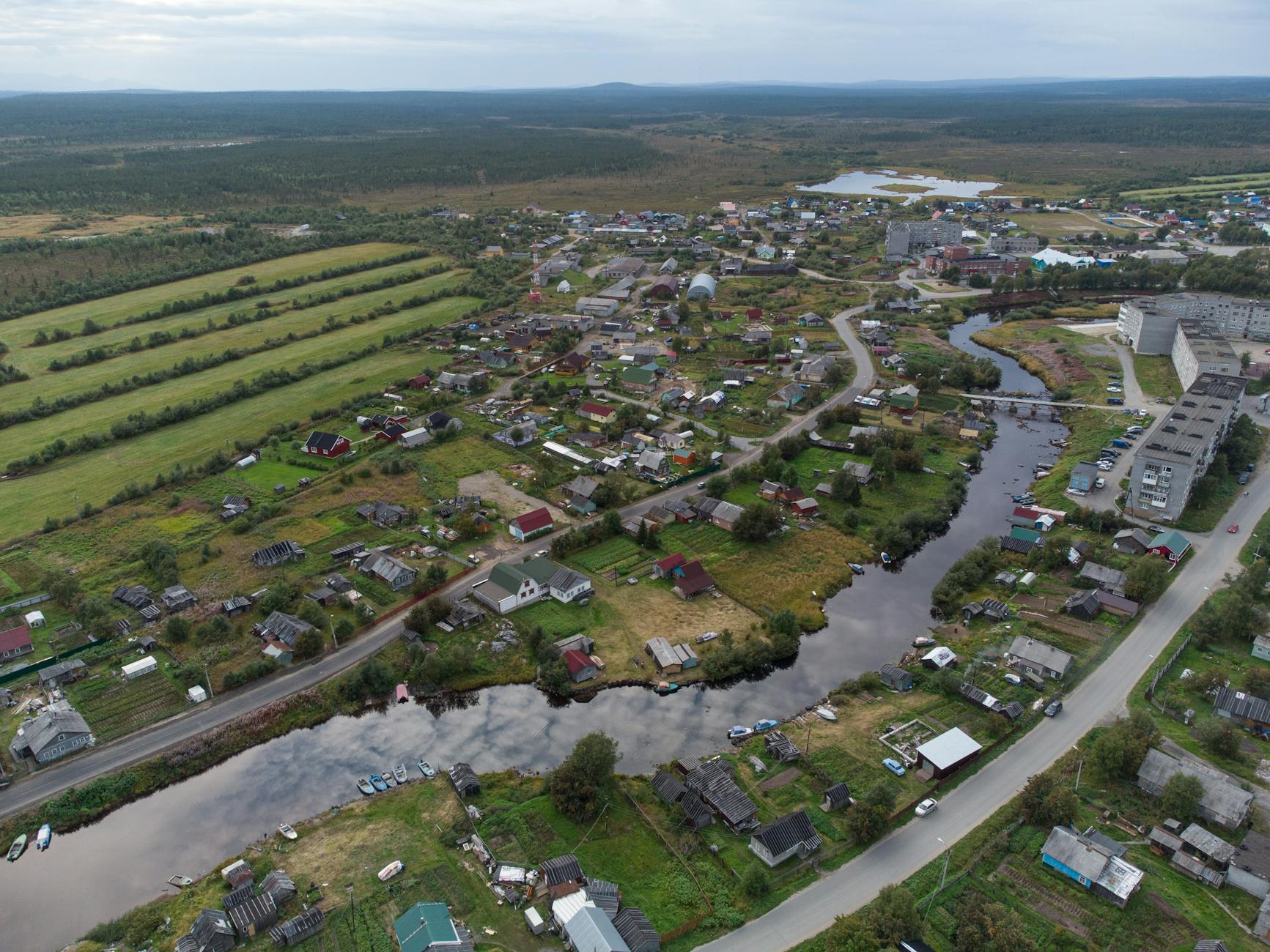 Lotniczy widok na wieś nad rzeką otoczoną polami i wzgórzami