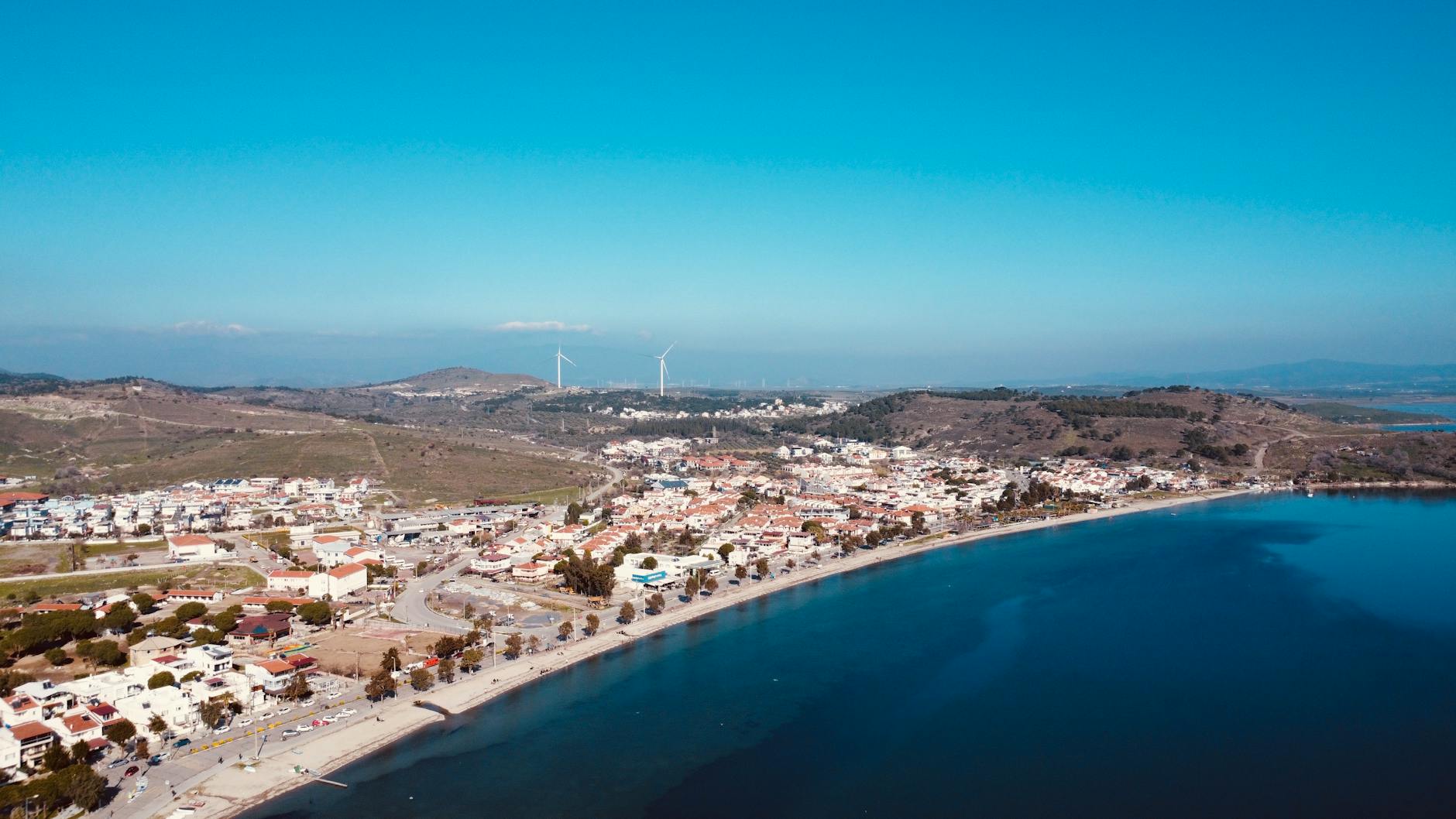 Nadmorskie miasteczko z lotu ptaka i turbiny wiatrowe na wzgórzach