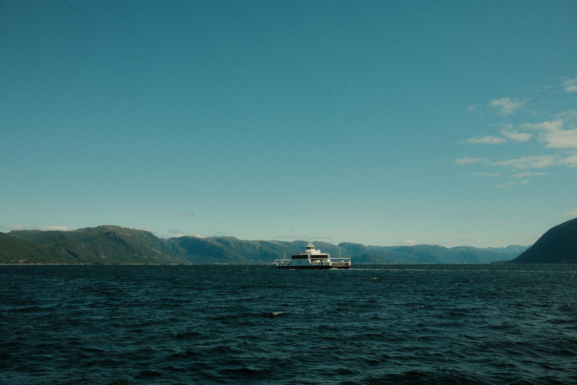 Prom pasażerski płynie przez spokojny norweski fiord w słoneczny dzień