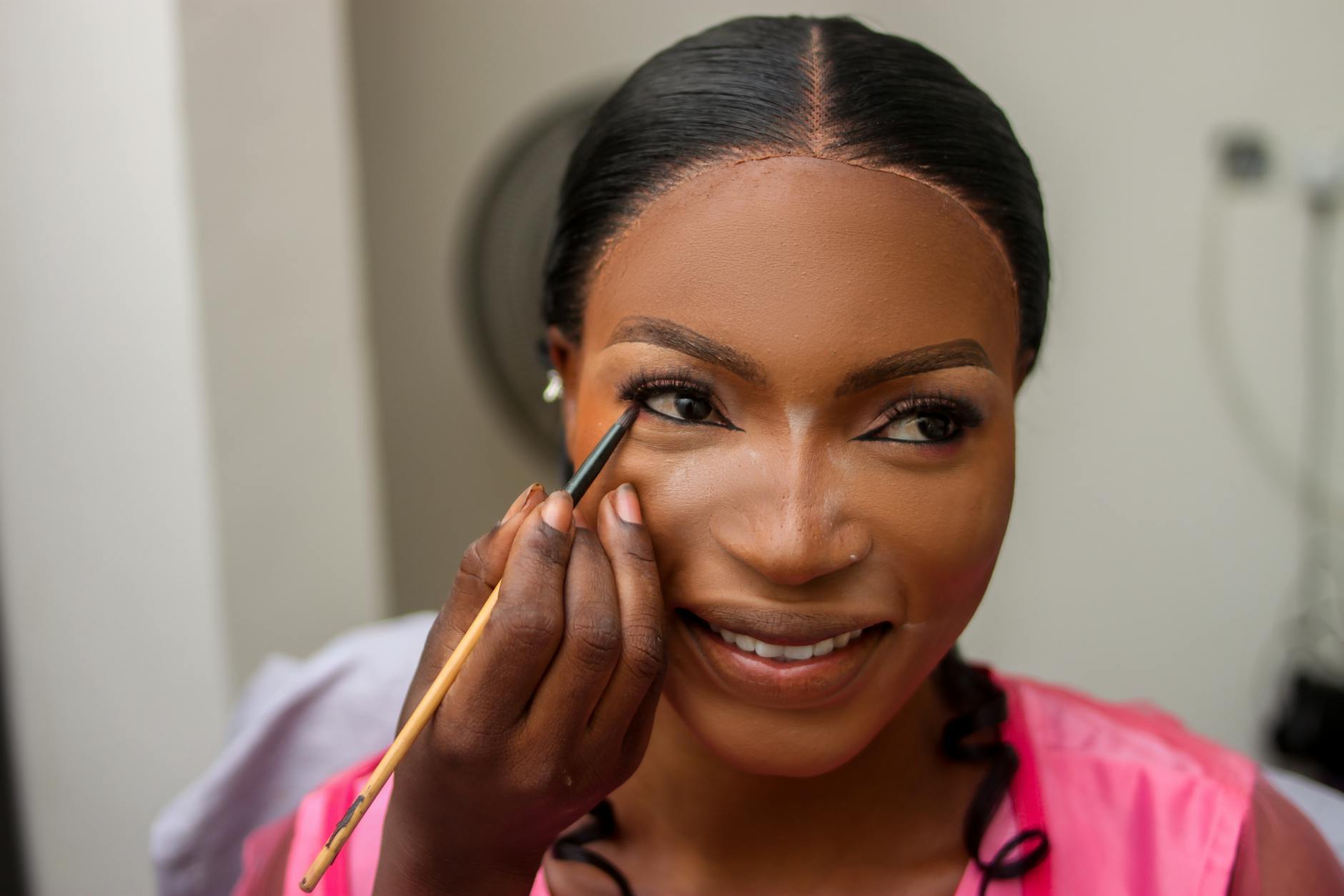 Uśmiechnięta panna młoda w Nigerii podczas nakładania makijażu ślubnego