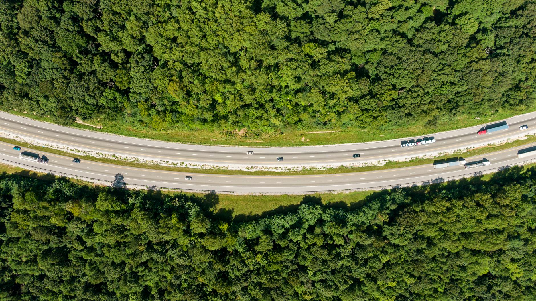 Autostrada z lotu ptaka przecinająca zielony las w pobliżu obszaru chronionego