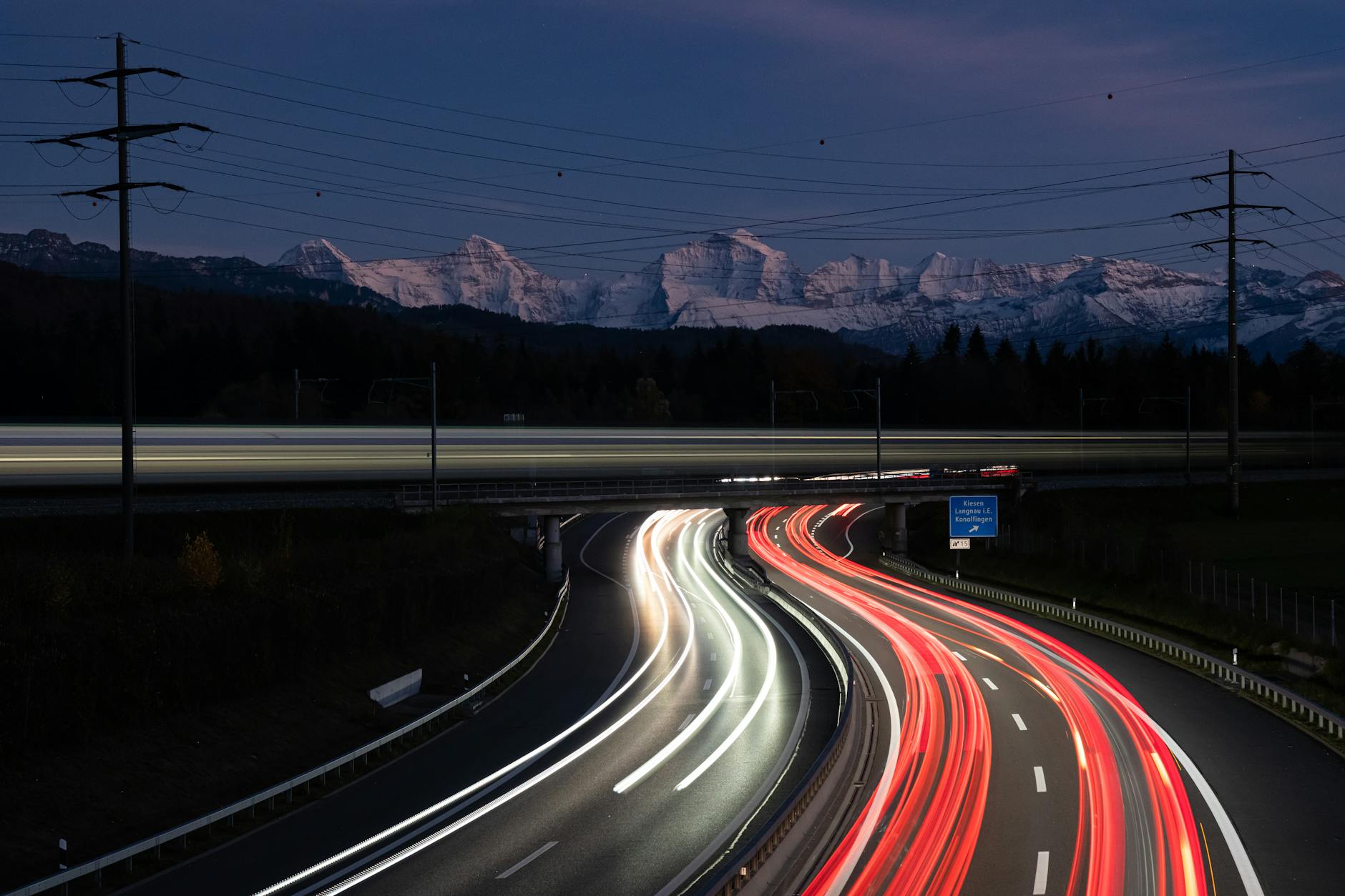 Nocna autostrada w Bernie, smugi świateł aut na tle ośnieżonych gór