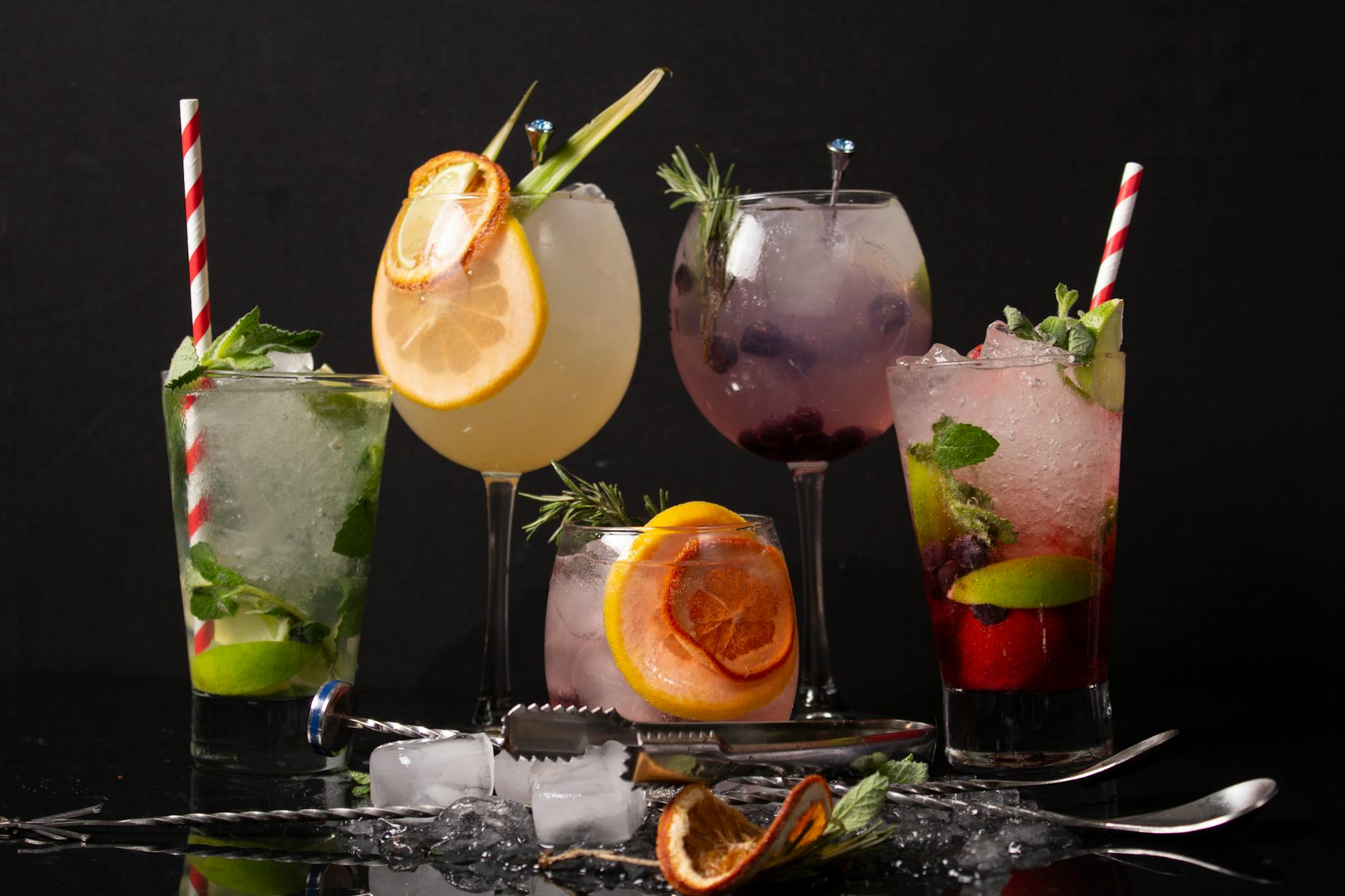 Różnokolorowe drinki z ginem w szklankach ozdobionych cytrusami