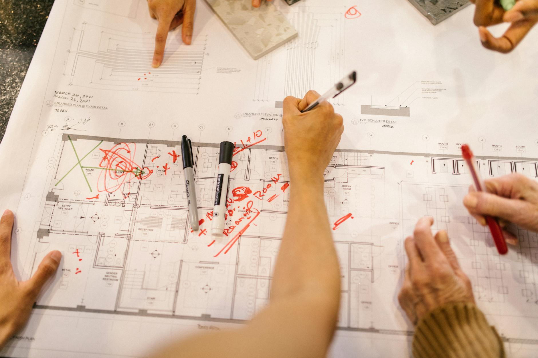 Zespół projektowy omawia plany zagospodarowania na rysunkach technicznych